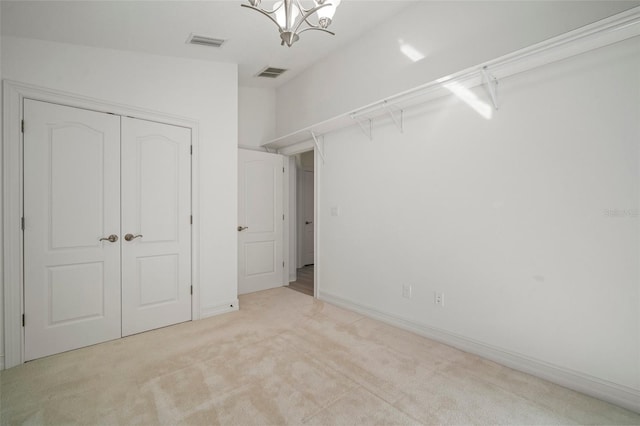 unfurnished bedroom featuring a chandelier, light colored carpet, and a closet