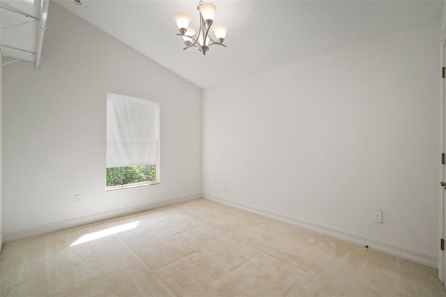 spare room featuring light carpet, a chandelier, and vaulted ceiling