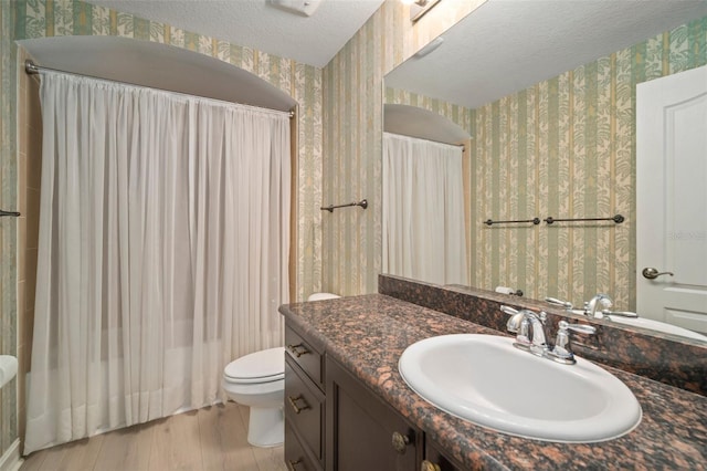 bathroom with vanity, toilet, a textured ceiling, curtained shower, and wood-type flooring