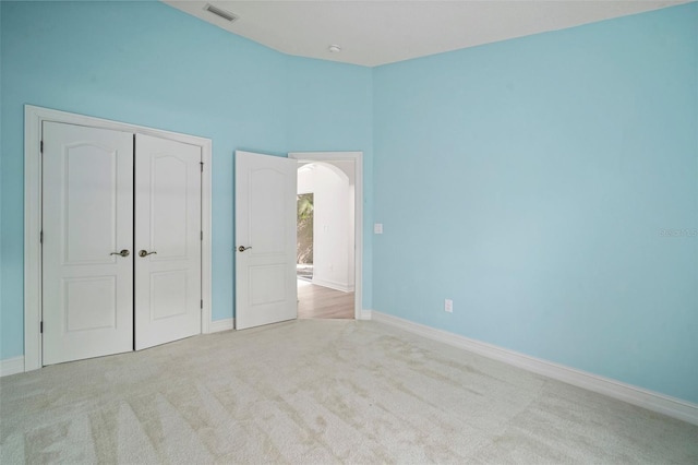 unfurnished bedroom with light colored carpet and a closet