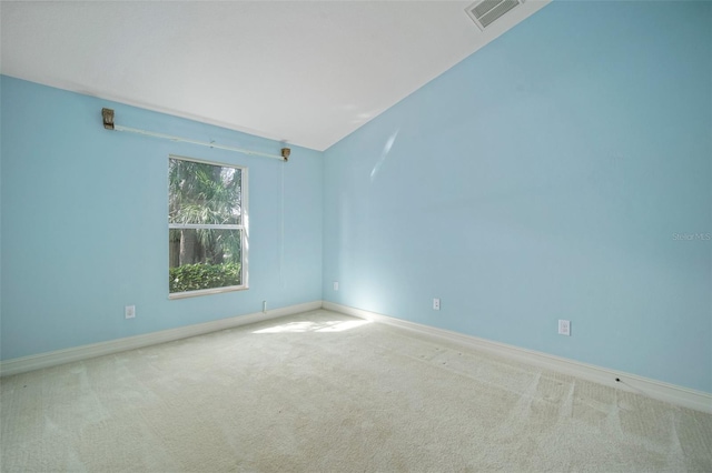 carpeted spare room featuring vaulted ceiling