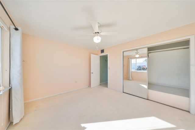 unfurnished bedroom with ceiling fan, light colored carpet, and a closet