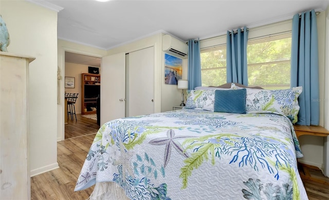 bedroom with an AC wall unit, hardwood / wood-style floors, crown molding, and a closet