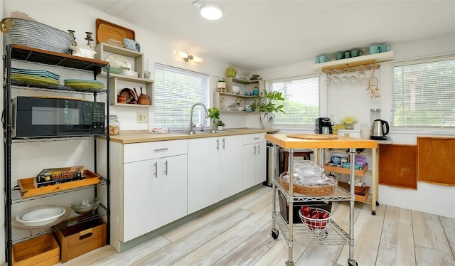 kitchen featuring white cabinets, a healthy amount of sunlight, sink, and light wood-type flooring