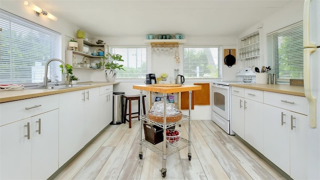 kitchen featuring white cabinets, a healthy amount of sunlight, sink, and white range with electric cooktop