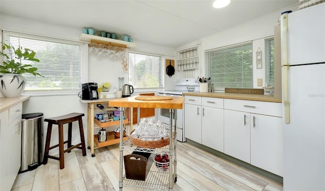 kitchen featuring white appliances, light hardwood / wood-style floors, a healthy amount of sunlight, and white cabinets