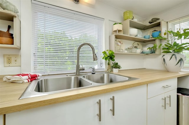 kitchen featuring a wealth of natural light, sink, white cabinets, and crown molding