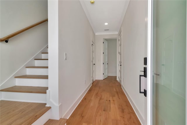 corridor featuring light wood finished floors, stairs, recessed lighting, baseboards, and ornamental molding