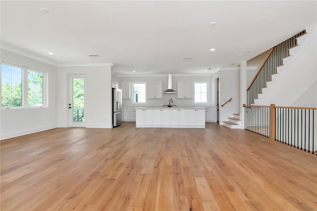 unfurnished living room with a sink, recessed lighting, ornamental molding, and light wood finished floors