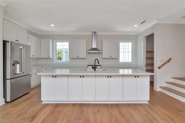 kitchen featuring high end fridge, light countertops, wall chimney exhaust hood, and a wealth of natural light