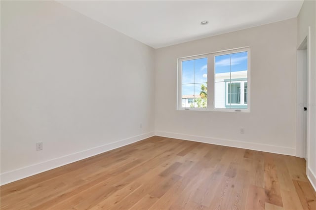 spare room featuring baseboards and light wood finished floors
