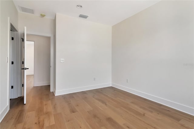 empty room featuring baseboards, visible vents, and light wood finished floors