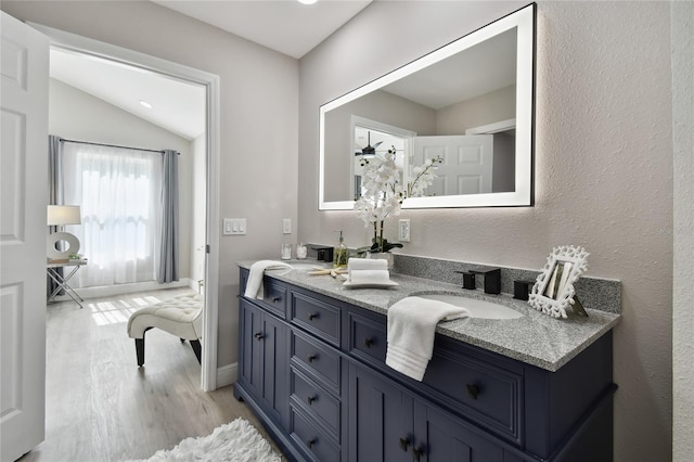 bathroom with hardwood / wood-style flooring, vanity, and vaulted ceiling