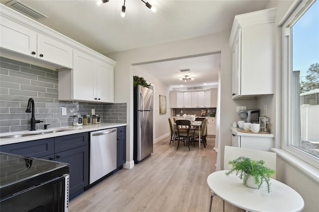 kitchen with blue cabinets, sink, white cabinetry, tasteful backsplash, and stainless steel appliances