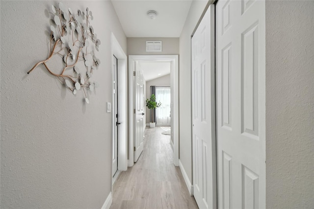 hall with vaulted ceiling and light hardwood / wood-style floors