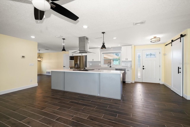 kitchen with island exhaust hood, a kitchen island, a barn door, and hanging light fixtures