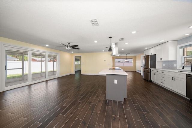 kitchen with a kitchen island, hanging light fixtures, white cabinetry, appliances with stainless steel finishes, and dark hardwood / wood-style flooring