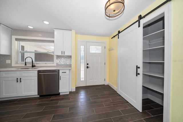 kitchen with dark hardwood / wood-style floors, backsplash, sink, stainless steel dishwasher, and white cabinets