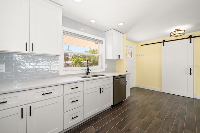 kitchen with sink, a barn door, stainless steel dishwasher, white cabinetry, and dark hardwood / wood-style flooring