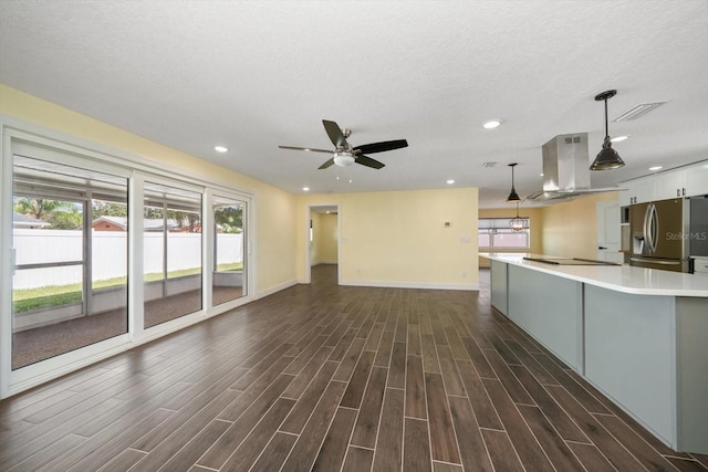 unfurnished living room featuring dark wood-type flooring, ceiling fan, and a textured ceiling