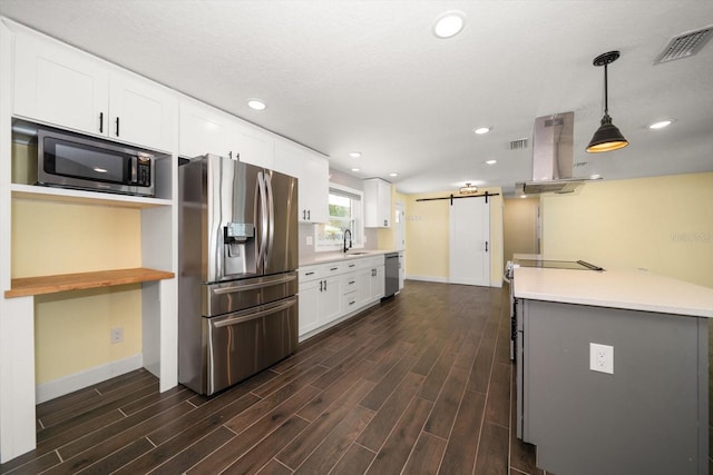 kitchen featuring dark hardwood / wood-style flooring, white cabinetry, a barn door, pendant lighting, and stainless steel appliances