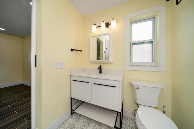 bathroom with toilet, vanity, and wood-type flooring