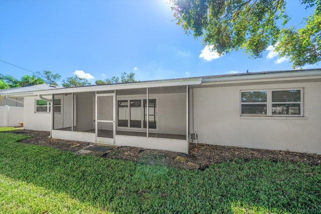 back of property with a lawn and a sunroom