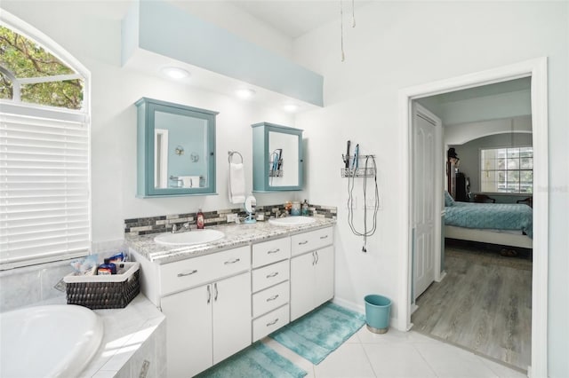 bathroom with vanity, a relaxing tiled tub, and tile patterned floors