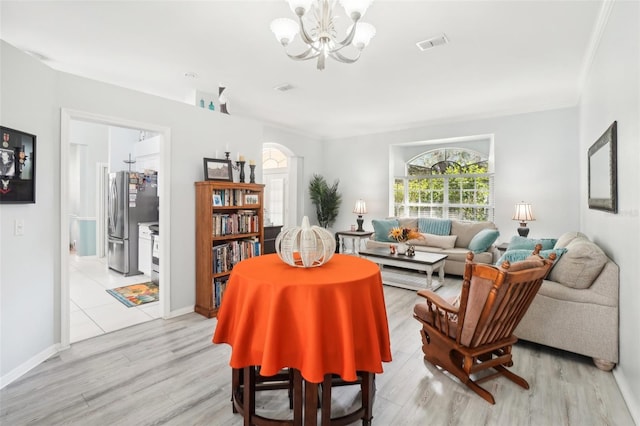 living room featuring crown molding, a notable chandelier, and light wood-type flooring