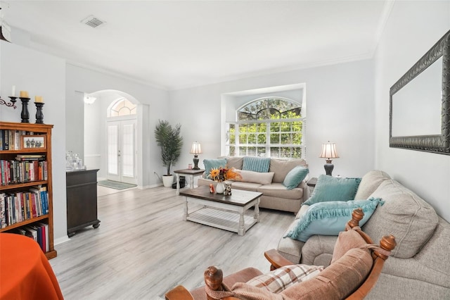 living room with light hardwood / wood-style floors, crown molding, and french doors