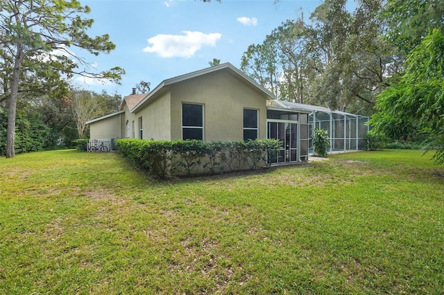 rear view of house with a lanai and a lawn