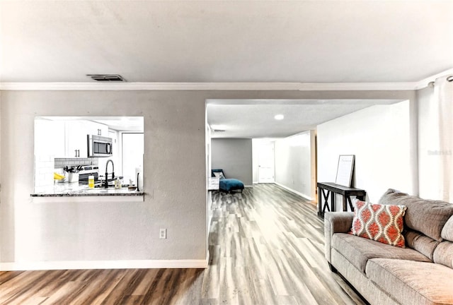 living room featuring baseboards, crown molding, and wood finished floors
