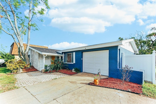 view of front of home featuring driveway, an attached garage, fence, and stucco siding