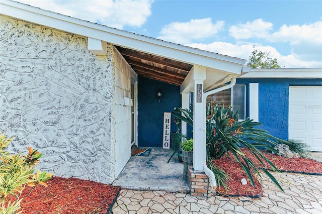 property entrance with an attached garage and stucco siding