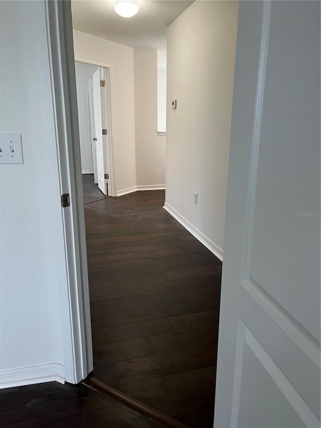 hallway featuring dark hardwood / wood-style floors and a textured ceiling