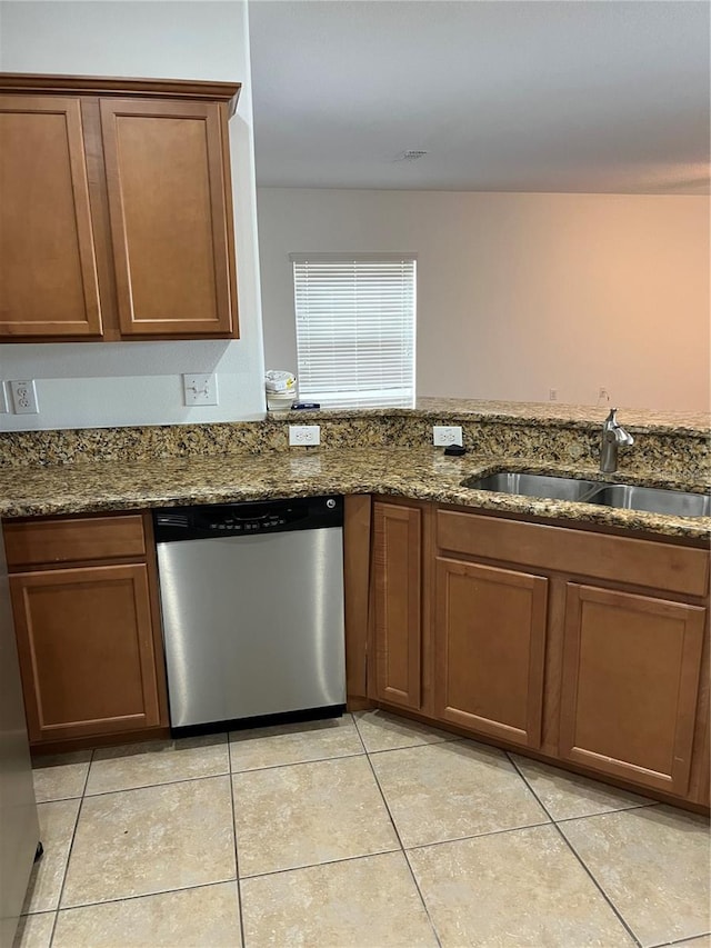 kitchen featuring dishwasher, light tile patterned floors, dark stone counters, and sink