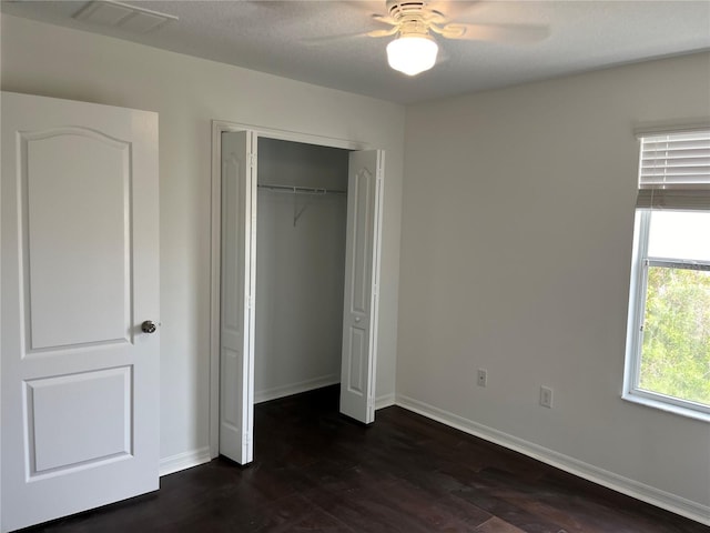 unfurnished bedroom featuring ceiling fan, dark hardwood / wood-style flooring, and a closet