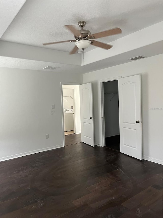 unfurnished bedroom featuring a walk in closet, a raised ceiling, ceiling fan, washer / clothes dryer, and a closet