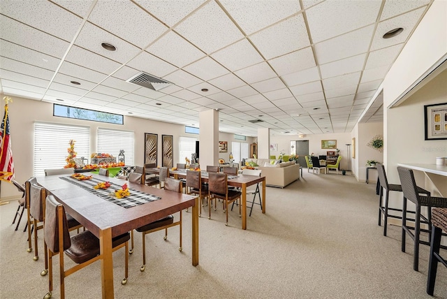 dining area with light carpet and a drop ceiling