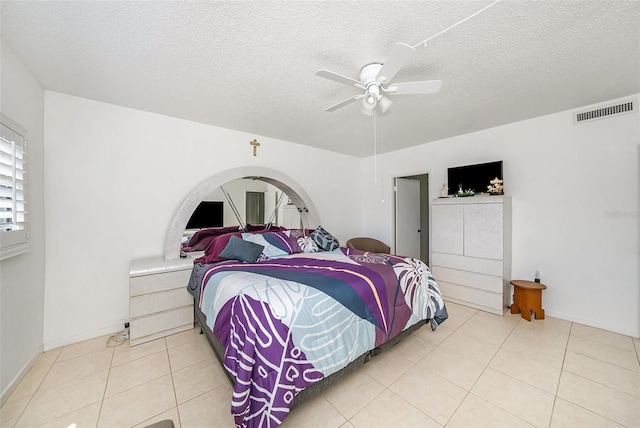 tiled bedroom with ceiling fan and a textured ceiling