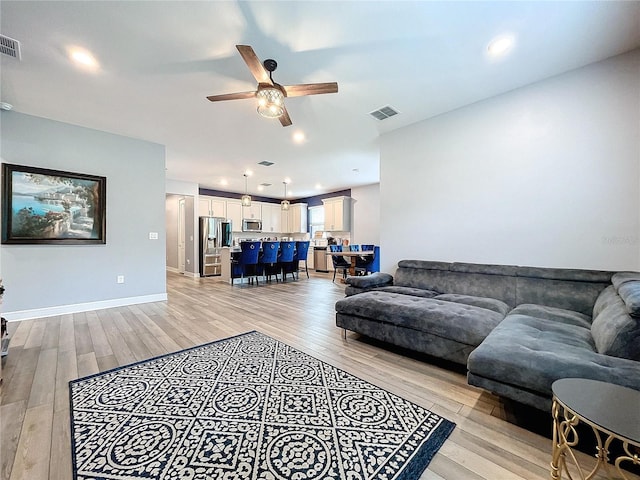 living room with light wood-type flooring and ceiling fan