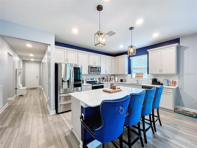 kitchen featuring a center island, light wood-type flooring, white cabinetry, and appliances with stainless steel finishes