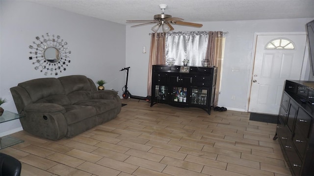 living room featuring ceiling fan, light wood-type flooring, and a textured ceiling