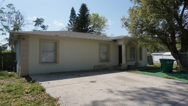 view of front of home featuring a patio area, fence, driveway, and stucco siding