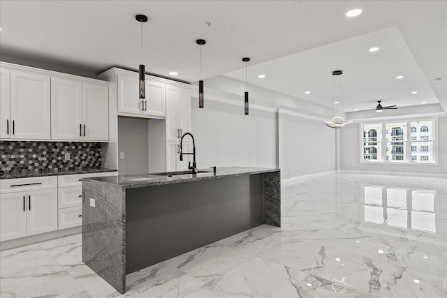 kitchen with white cabinets, hanging light fixtures, ceiling fan, and dark stone countertops