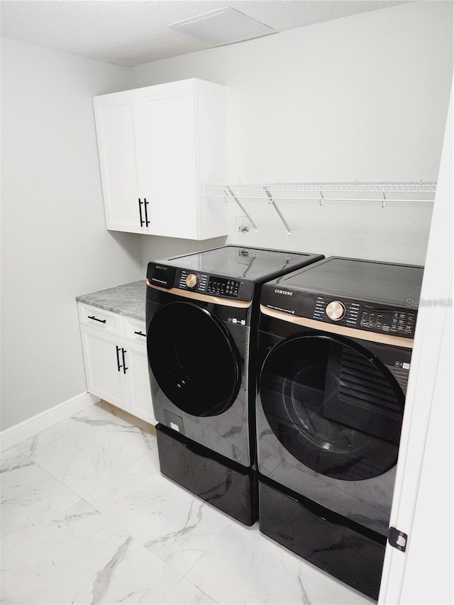 211 Dolphin Pt Unit 202, Clearwater Beach, FL 33767 - laundry area featuring independent washer and dryer, cabinet space, light marble finish flooring, and baseboards