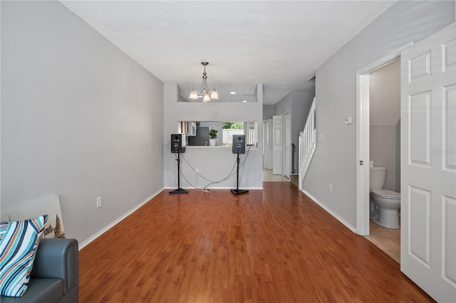 unfurnished living room featuring hardwood / wood-style floors, a textured ceiling, and an inviting chandelier