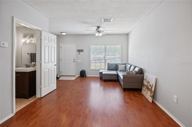 living room with hardwood / wood-style floors, a textured ceiling, and ceiling fan