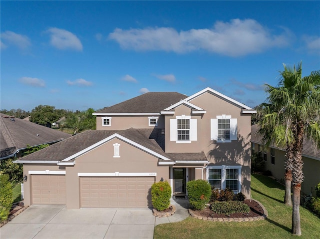 traditional home with concrete driveway, a garage, a front yard, and stucco siding