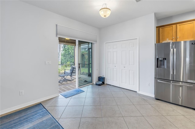 kitchen featuring brown cabinets, baseboards, light tile patterned floors, and stainless steel fridge with ice dispenser